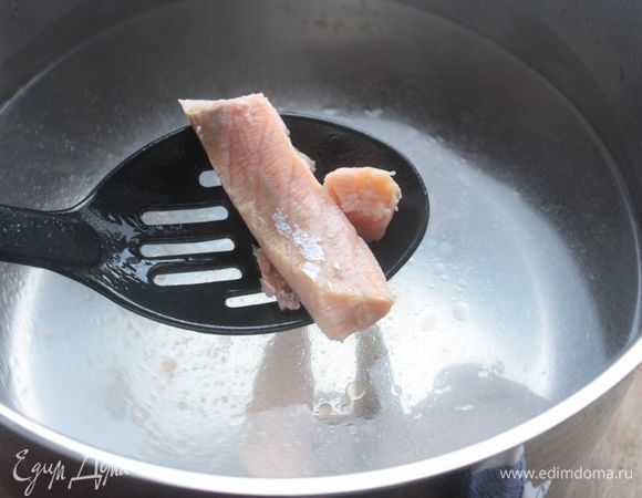 Рыбу порежьте на некрупные куски (сильно мелкими их делать не нужно). Луковицу очистите и разрежьте на 2 половины. Опустите лук и рыбу в кипящую воду. Рыба приготовиться за 5-7 минут в зависимости от размера кусочков. Аккуратно выньте ее шумовкой и отложите на время в отдельную емкость.