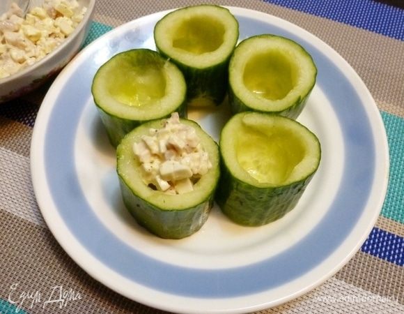 Длинноплодный огурец нарезать на одинаковые бочонки. Чайной ложкой вынуть мякоть огурца, не трогая дно. Заполнить каждый стаканчик начинкой.