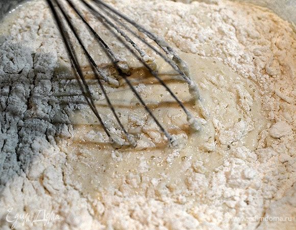 Добавьте муку, просеянную с содой. Перемешайте, чтобы не было комочков, постепенно вливая оставшееся молоко. Добавьте подошедшую дрожжевую смесь, тщательно перемешайте. Накройте и поставьте в теплое место подниматься на 1 час. Через час перемешайте и оставьте еще на час.