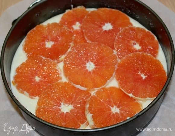 Выложить тесто в форму на 20 см, апельсины очистить, порезать тонкими кружочками, выложить сверху на тесто.