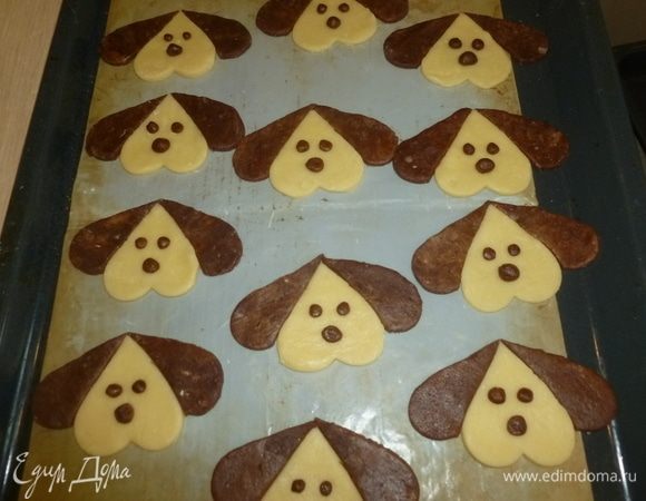 Противень застелить пергаментной бумагой или тефлоновым листом для выпечки. Выложить на противень перевернутое светлое сердечко, а из половинок тёмного выложить по бокам ушки. Из остатков шоколадного теста скатать маленькие шарики и выложить их на светлое тесто в форме глаз и носа собачки. Выпекать 10-15 минут в середине разогретой до 180°С духовки.