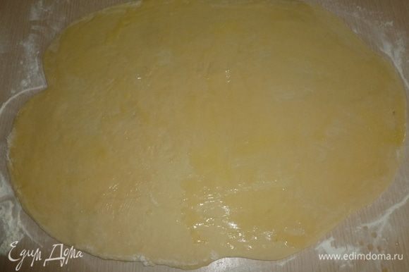 Тесто обмять, раскатать в прямоугольник 65х45 cм. Растопить оставшееся масло и смазать тесто.