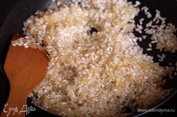 Добавить к луку рис, перемешать, чтобы каждая рисинка была в масле. Рис ни в коем случае предварительно не промывать.