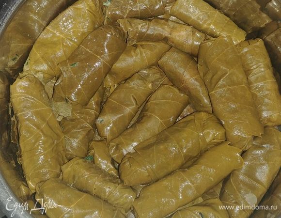 Тоже самое мы проделываем со всеми остальными листами и выкладываем их в кастрюльку, плотно прижимая друг к другу. Затем закрываем тарелкой и заливаем кипяченой водой. Залить надо не до конца, а так чтобы верхний слой хорошо виднелся, он отлично приготовится и на пару, иначе воды будет сильно много и долма переварится. Варить ее надо до тех пор, пока вся вода не испарится из кастрюли. Чтобы проверить есть ли еще вода на дне, то можно немного наклонить кастрюльку в сторону и если видите воду, то надо еще немного поварить. Подавать долму можно с натуральным йогуртом.