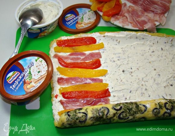 Остывший рулет развернуть и промазать сливочным сыром (у меня со вкусом лесным грибов). На сырную начинку уложить нарезанные запеченные перцы и подкопченные ломтики бекона.