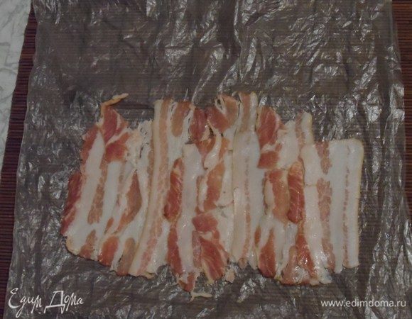 Выложить на циновку бекон по длинне ролла с сыром.