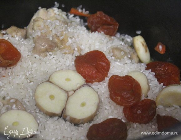 Добавить к курице и овощам рис ТМ «Националь», разровнять. Добавить чеснок и курагу.