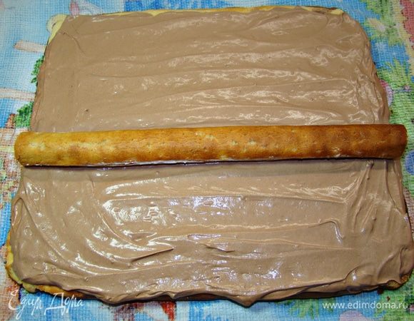 Крем равномерно нанести на поверхность бисквита (часть крема останется для обмазывания готового «полена»). В серединку положить заварное пирожное и все аккуратно завернуть в виде рулета. Рулет завернуть в пищевую пленку и поставить в холодильник на 2–3 часа.