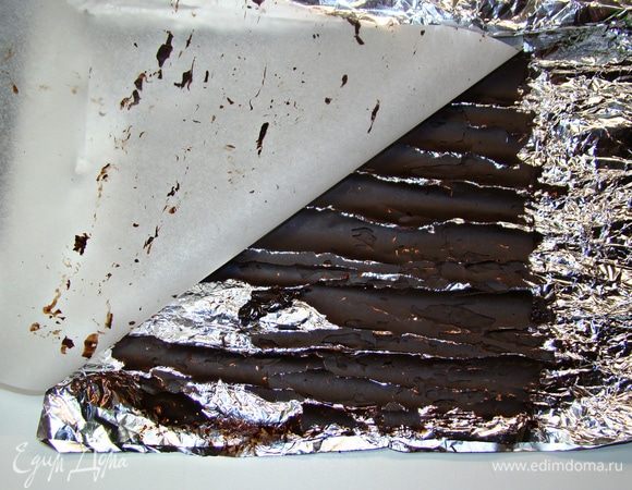 На водяной бане растопить плитку темного шоколада. Лист фольги помять, делая заломы в виде коры дерева. Затем сверху равномерно нанести растопленный шоколад. Накрыть листом пекарской бумаги и все аккуратно свернуть в рулончик. Поставить в холодильник для застывания.