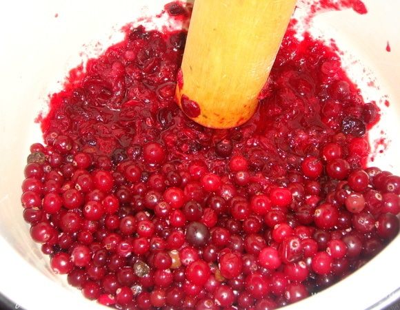 Клюкву выложить в дуршлаг, промыть, дать стечь лишней жидкости. Сложить клюкву в кастрюлю и помять толкушкой. Марлю сложить в два слоя, брать по 1 столовой ложке клюквенного пюре, отжать сок в отдельную посуду. 
