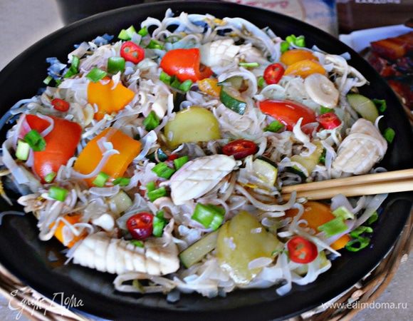 Вернуть вок на огонь, вновь разогреть масло, добавить имбирь, чеснок. Далее — болгарский перец и обжаривать, постоянно помешивая, 5 мин. Влить рисовое вино, соевый соус, довести до кипения и добавить подготовленные кальмары. Хорошо все перемешать.