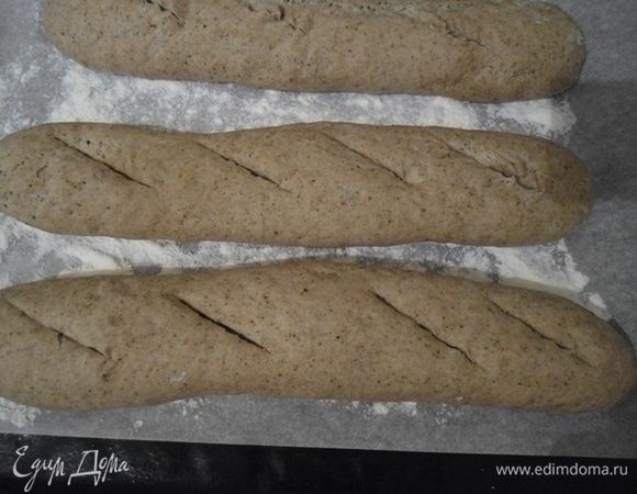 Сделайте надрезы. Духовка разогрета до 230°С. Нужно поставить вниз духовки чашку с кипящей водой или бросить несколько кубиков льда, чтобы создать пар. Поставить багеты на 10 минут. Убавить температуру до 200°С, открыть духовку, выпустить пар или убрать чашку с водой и оставить багеты допекаться еще на 20 минут.