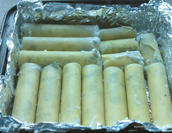 Приготовьте соус «Бешамель»: растопите сливочное масло и обжарьте на нем ложку муки. После чего добавьте молоко и варите, помешивая, на среднем огне, пока соус не загустеет. В конце посолите по вкусу.
Немного соуса распределите по основанию формы, сверху выложите каннеллони, чтобы они плотно прилегали друг к другу.