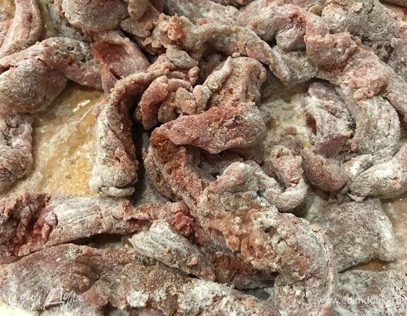 Кусочки мяса обвалять в муке, выложить к луку и обжаривать до появления румяной корочки.