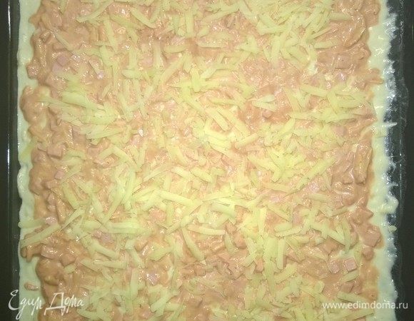 Получившуюся массу выкладываем на тесто и распределяем по нему. Сверху засыпаем оставшимся тертым сыром и ставим запекаться на 30 минут в духовой шкаф, разогретый до температуры 200-210°C.