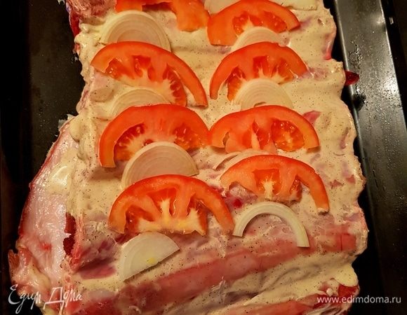 Перед тем, как отправить ребра в духовку, делаем небольшие надрезы и укладываем туда помидоры и лук, нарезанные полукольцами.