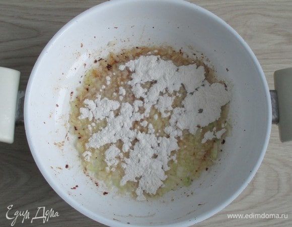 Переключитесь на слабый огонь и добавьте к луку муку. При помешивании напитайте муку жиром и слегка обжарьте ее.