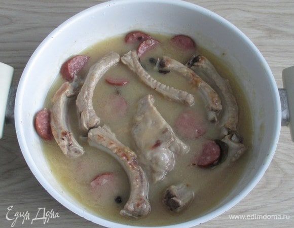 Доведите соус с мясными ингредиентами до закипания. Затем тушите, а точнее, томите ребрышки с колбасой на слабом огне около одного часа. В конце приготовления добавьте в пряженину давленый или измельченный чеснок.