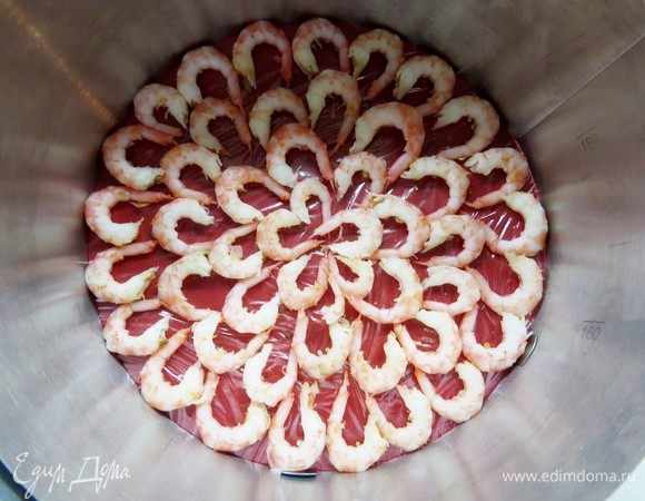 Форму смазываем тонким слоем растительного масла, чтобы легче было вынуть салат. Я использовала регулируемое кольцо для сборки тортов. Форму маслом не смазывала, но проложила бока формы гибкой пленкой. Таким образом, бока нашего закусочного торта точно не повредятся. 
Собираем закусочный торт вверх ногами.
На дно формы выкладываем по кругу очищенные креветки. 