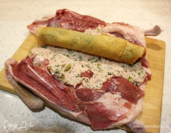 Половину фарша распределить в области спинки, создавая плоскую подложку. Перенести на нее первый рулет. Не размещайте рядом рулеты со шпинатом и черносливом, это будет некрасиво на поперечном разрезе.