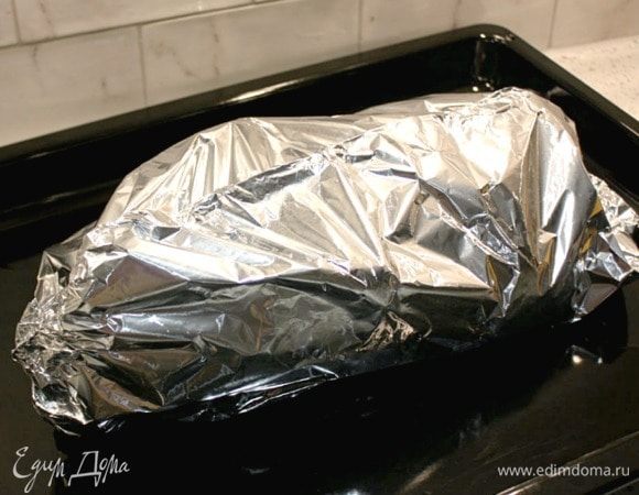 Большой кусок фольги и всю поверхность утки смазать растительным маслом, иначе часть кожи во время запекания пристанет к фольге. (Я беру 2 больших куска фольги, накладываю один на другой и сгибаю узкой полоской вместе 5–6 раз по длинной стороне. Разворачиваю листы и плотно приглаживаю этот шов).
Уложить фольгу на широкий противень, на нее утку, спинкой вниз. Края фольги соединить над уткой и плотно свернуть.