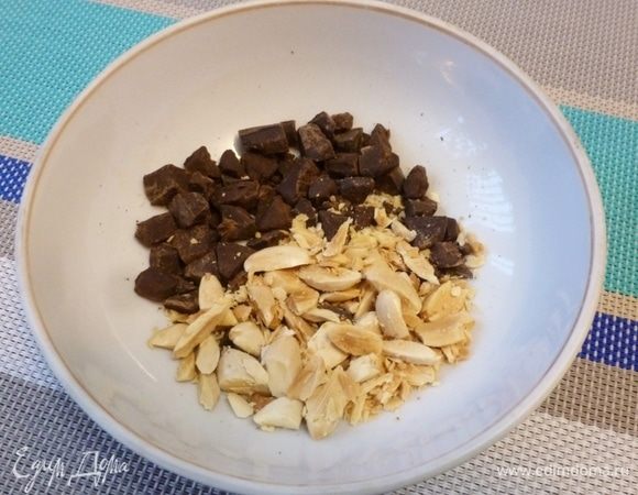 Измельчить кусочек шоколада на кусочки. Подсушенный миндаль нарубить.