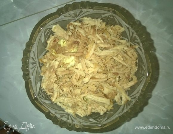 Затем отделяем сваренное куриное мясо от костей, нарезаем его тонкой соломкой и выкладываем в вазу для салата.