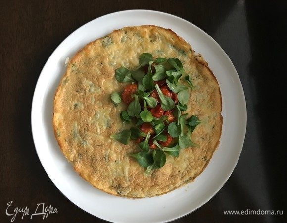 Перекладываем готовый омлет в тарелку, на одну половину выкладываем листья шпината и помидоры. Второй половиной накрываем.