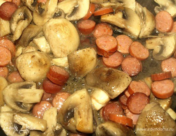 Охотничьи колбаски мелко режем. Добавляем к грибам. Обжариваем.