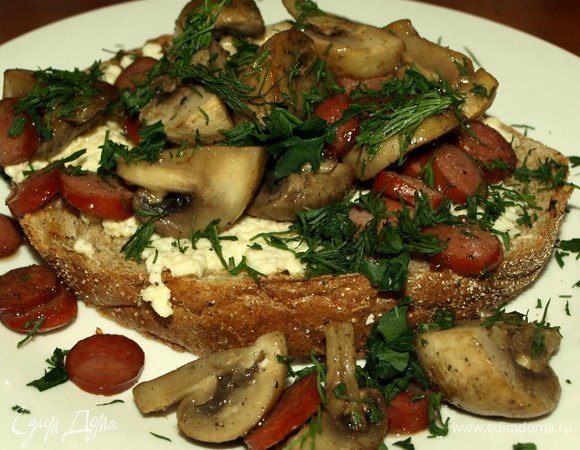 На хлеб выкладываем омлет, сверху грибы с охотничьими колбасками, посыпаем рубленой зеленью. 