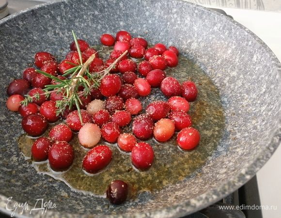 На сковороду с утиным жиром высыпать замороженную клюкву, добавить зубчик чеснока, по веточке пряных трав, соль, сахар, черный перец по вкусу. На слабом огне доведите до кипения, влейте 25 грамм коньяка и варите до выпаривания жидкости на 1/3. 