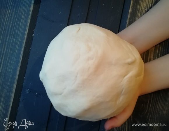 Замешиваем тесто тем же венчиком или ложкой, затем добавляем масло и продолжаем замес руками. Тесто получается мягким и эластичным. Отбиваем его об стол 50 раз. Тесто должно стать мягким, плотным, очень эластичным.