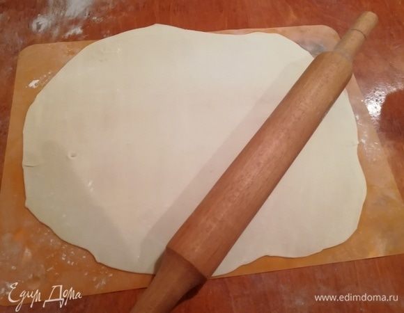 Духовку включаем на 180°С. Растапливаем сливочное масло. Выстилаем противень бумагой для выпечки. Берем подготовленное тесто, раскатываем на присыпанном мукой столе «колбаску» и нарезаем на 12 частей. Долее я взяла силиконовый коврик, можно взять заранее подготовленную разглаженную ткань и работать на ней. Посыпаем мукой, раскатываем тесто аккуратно и тонко.
