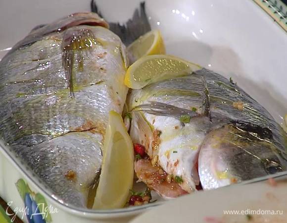 На коже рыбы сделать неглубокие поперечные надрезы, выложить ее в жаропрочную керамическую посуду и наполнить брюшки ореховой начинкой, затем слегка сбрызнуть дораду оливковым маслом, сверху и вокруг разложить дольки лимона, посолить и поперчить.