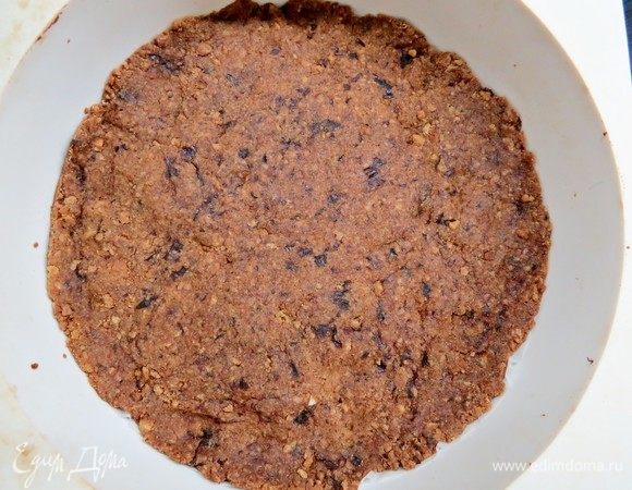 В кольце, разъемной форме или порционных формочках сформировать основу будущего чизкейка (у меня форма диаметром 18 см). Я сделала основу без бортиков. 
Основу охладить в холодильнике в течение 10 минут, потом подпечь в разогретой до 180°С духовке в течение 7–10 минут. Запеченную основу охладить. 