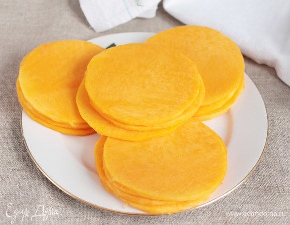 Тыкву нарезать тонкими пластинами по 3 мм. Площадь пластин должна быть такой, чтобы можно было вырезать из них кружочки (16 шт.) диаметром 9 см или квадратики, по желанию.  Из обрезков, удалив с них кожуру, можно сварить пюре, кашу или просто отдельно запечь. 