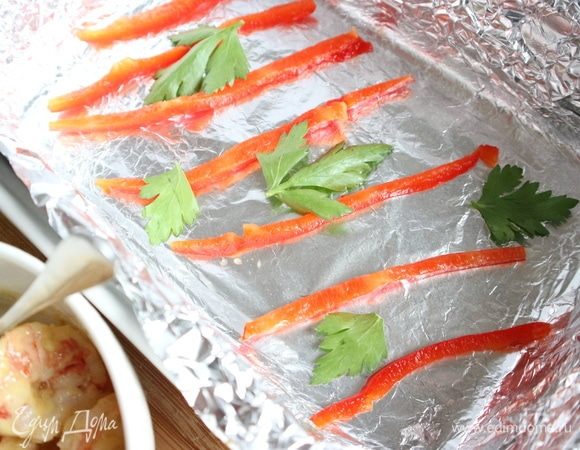 Красный болгарский перец (не очищать от шкурки), нарезать на полоски, обсушить на бумажной салфетке. Положить в форму, застеленную фольгой и смазанную оливковым маслом, наискосок, шкуркой к фольге. Дополнить зеленью (несколько листиков).