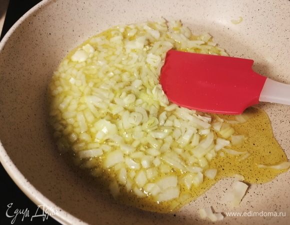 В сковороде нагреть оливковое масло. Лук нарезать кубиками, чеснок раздавить лезвием ножа. На среднем огне жарить лук, пока он не станет золотистого цвета. Чеснок извлечь. Поставить кастрюлю с водой на огонь. 
