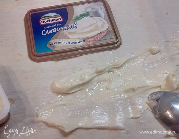 Лаваш разделить на две части и смазать хорошим слоем сливочного сыра Hochland, он защитит наш лаваш от промокания и даст нежный вкус нашим роллам.