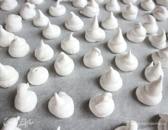 С помощью кондитерского мешка отсадить на противень, застеленный бумагой для выпечки, небольшие безе на некотором расстоянии друг от друга. Поместить противень с безе в духовку примерно на час. Духовку во время выпечки не открывать.