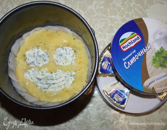 Сливочный сыр Hochland смешаем с чесноком и зеленью. В картофельном пюре сделаем несколько отверстий (но не до самого дна формы), выложим туда сырную массу. Форму сверху покроем фольгой.