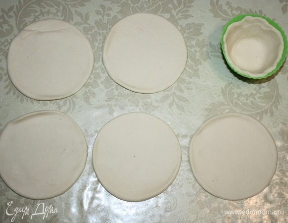 Слоеное тесто раскатать. Вырезать кружки. Каждый кружок поместить в форму. 