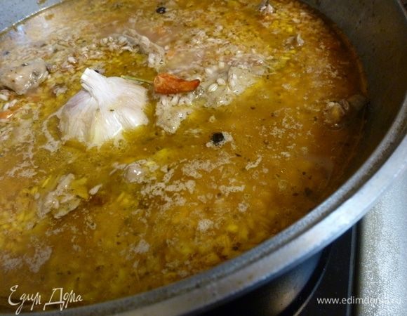 Выложить на курицу рис. Залить водой на 2 см выше риса. Воткнуть в рис головку чеснока. И перец чили (по вкусу). Чеснок не чистить, просто хорошо помыть. Когда закипит, убавить огонь и варить 30–40 минут. Выключить огонь, прикрыть полотенцем и так оставить на 15 минут. Затем перемешать рис с мясом.