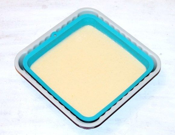 Берем формочку для выпечки 20х20 см (смазываем маслом) или силиконовую (не смазываем маслом), и выливаем тесто, разравниваем. Выпекаем корж в хорошо разогретой до 180°С духовке до золотистого верха, ~25-30 минут. Через 20-25 минут проверяйте корж на сухую спичку. 
Испеченный корж немного остывает в формочке. Если при выпечке образовалась у коржа верхушка, ее срезаем. Корж после выпечки пористый, мягкий немного золотистый. Срезанную верхушку коржа просушить в духовке и раскрошить, пойдет для украшения тортика.
