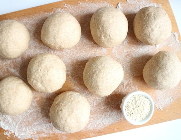 Духовку разогреть до 200°С. Достать подошедшее тесто из миски, разделить на 9 равных частей. Сформировать круглые булочки, положить их на рабочую поверхность, присыпанную мукой. Оставить их на 20-25 минут.