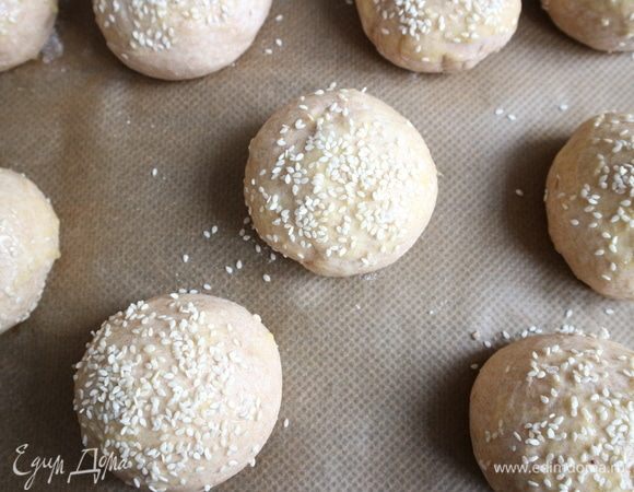 Противень застелить бумагой для выпечки. Булочки кисточкой смазать желтком, посыпать кунжутом. Выпекать булочки 30 минут до золотистого цвета.