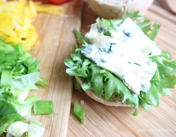 На нижнюю часть булки положить немного соуса, листики салата. Затем сыр с голубой плесенью.