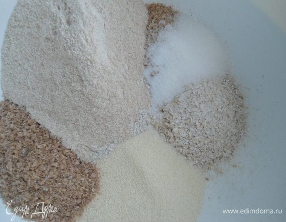 Овсяные и гречневые хлопья измельчить. В большой миске смешать хлопья, отруби, манку,  сахар и соль. 