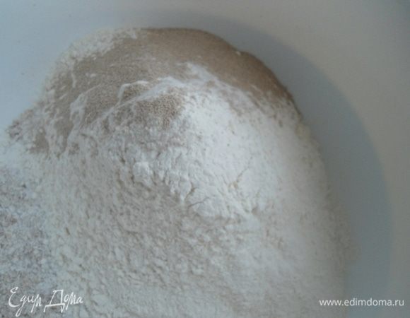 Муку просеять и добавить к сухой смеси вместе с дрожжами. Размешать. 
