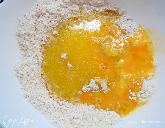 В сухие ингредиенты добавить растопленное сливочное масло и яйцо, хорошо перемешать. Должно получиться рассыпчатое песочное тесто.